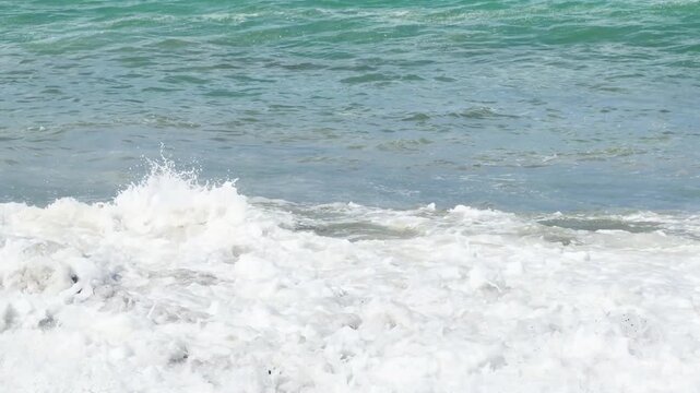 Blue sea and large waves and foam. Wave splashing over pebbles at sea. Rolling ocean waves. Summer beach background. Powerful sea waves	
