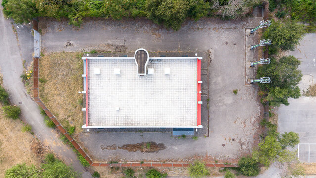 Aerial view of an electrical utility building with a flat roof and surrounding gravel lot, situated near the Assago Metro infrastructure in Assago, Lombardy, Italy.