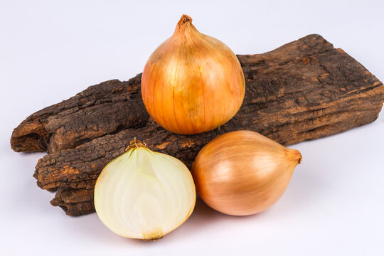 Fresh yellow onions whole and half on rustic wooden board isolated on white background.