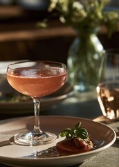 Naklejka premium Glass of a pink cocktail on a table. the glass is tall and slender with a wide base and a narrow stem. it is filled with a pinkish-red liquid, which appears to be a cocktail.