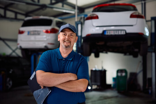 Portrait of confident mature mechanic in car workshop looking at camera.