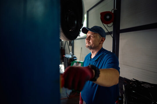 Mature mechanic using hydraulic lift during car service in garage.