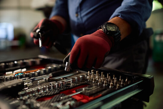 Close up of car mechanic taking socket wrench from professional toolbox in garage.