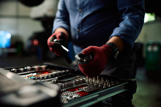 Close up of mechanic selecting socket wrench for car repair in garage.