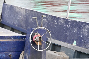 Steering Wheel on a Blue Fishing Boat Moored at a Harbor Bollard © Miroslaw
