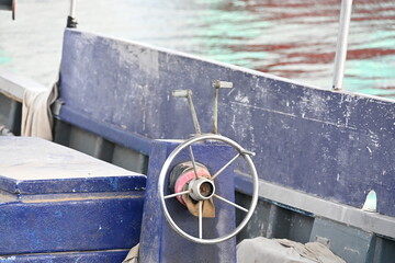 Steering Wheel on a Blue Fishing Boat Moored at a Harbor Bollard © Miroslaw