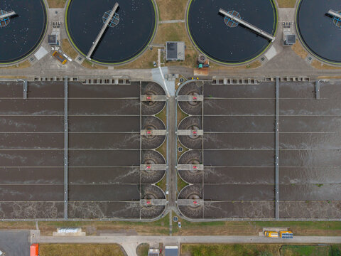 Aerial view of a wastewater treatment plant with circular sedimentation tanks and aeration basins in the Netherlands.
