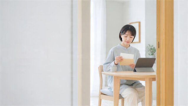 自宅で書類とタブレットを確認する女性