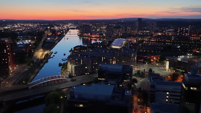 Aerial view of Manchester city center skyline at sunset reflecting over the water