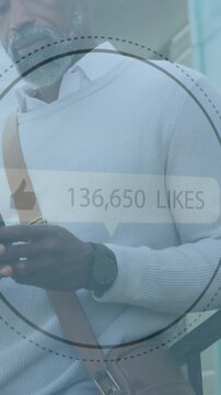 Thumbs up icon with increasing likes against african american senior man using smartphone