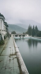 Fototapeta premium Traveler walking beside an abandoned mountain pool beneath misty forested hills.