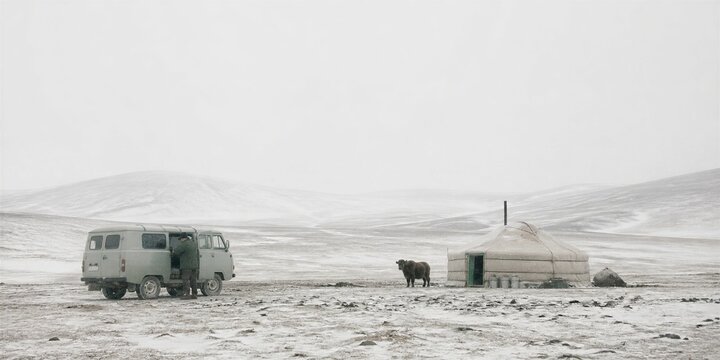 Offbeat winter expedition with rugged vehicle, yurt, and grazing yak across a remote snow-covered mountain landscape.