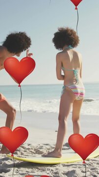 Animation of heart icons over couple with surfboard on beach