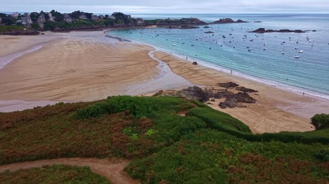 Longchamp Beach at Saint-Lunaire, Ille-et-Vilaine, Brittany, France, overlooking the English Channel and Emerald Coast with anchored boats, sandy bay, coastal heath and tidal shoreline, drone flyover