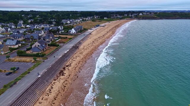Drone flies above Longchamp Beach, Saint-Lunaire, Ille-et-Vilaine, Brittany, France, revealing the coastal promenade, stepped seawall, sandy beach, English Channel and Emerald Coast.