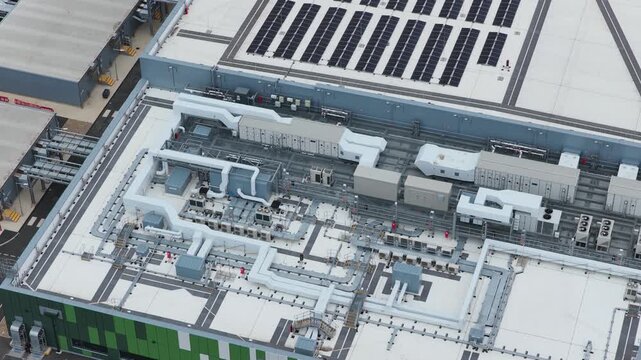 Modern industrial building exterior showing ventilation systems and server infrastructure on the rooftop of a busy technological site located in a large metropolitan business park area