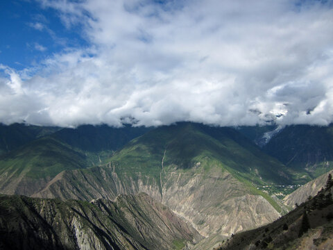 Breathtaking mountain range with clouds covering the peaks under a blue sky