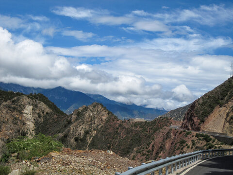 Scenic mountain road with blue sky and white clouds in the distance