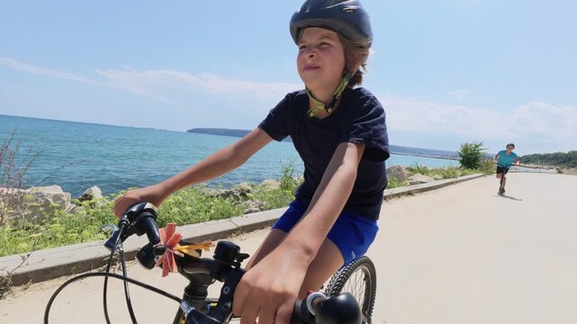Boy Riding Bicycle along Sea Coast POV