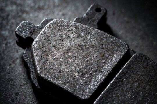 Close view of old worn car brake pads showing metal friction material. These parts are for vehicle repair and maintenance. Need replacement for car safety.
