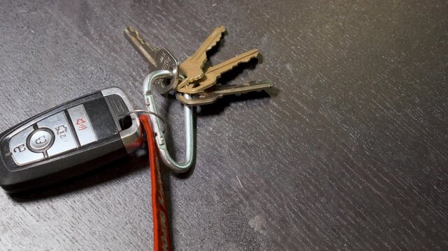 Sliding keys and key fob onto a black desk.