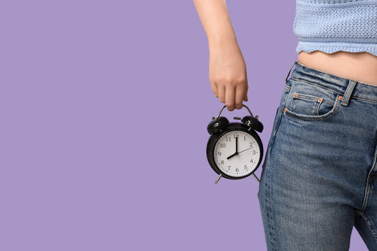 Woman holding a black alarm clock, time management and punctuality concept, deadline and schedule planning