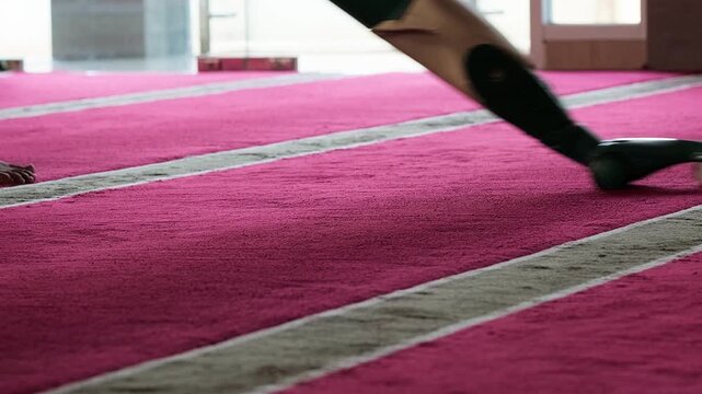 Close-up of a vacuum cleaner cleaning a mosque carpet.