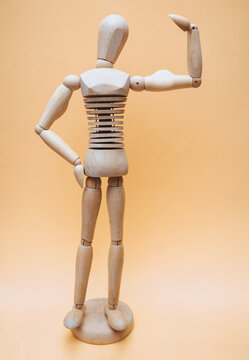 Wooden bodybuilder mannequin shows muscular arms on a beige background. Concept of physical strength and exercise with the gym.