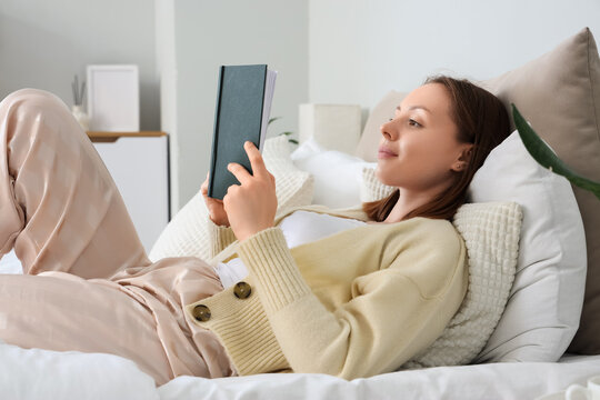 Young woman relaxing in bed reading a book, leisure and self care at home, Comfortable lifestyle and mental wellness
