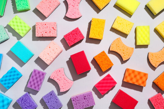 Colorful cleaning sponges and kitchen scourers in various shapes and sizes on a light gray background household chores, this assortment household chores hygiene and domestic cleaning tasks