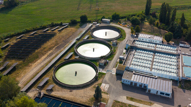 Aerial view of the Depuratore di Assago wastewater treatment plant with circular sedimentation tanks, treatment basins, and solar panels in Assago, Lombardia, Italy.
