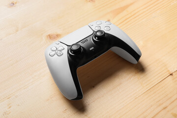 White and black modern video game controller on a light wooden table, gaming and entertainment technology, the electronic device features joysticks and buttons © Pixel-Shot