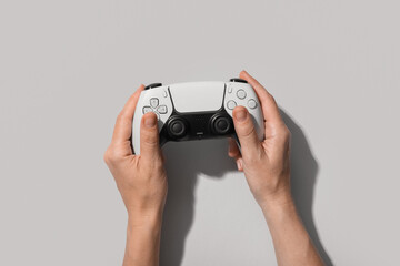 Person holding a white video game controller with both hands, top view on a light gray background © Pixel-Shot