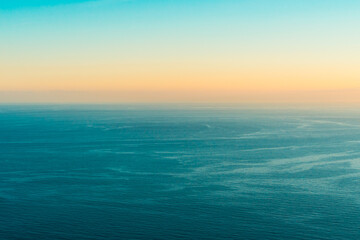 Aerial view of calm blue ocean water surface during sunset horizon © Nazar