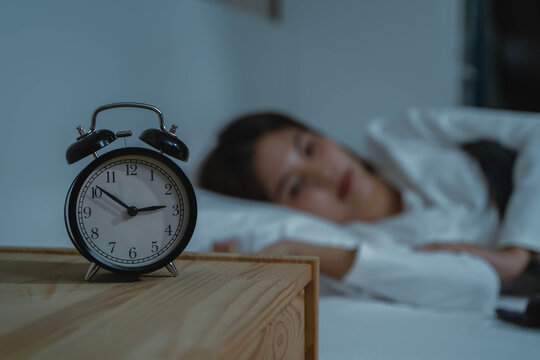 Young woman sleepless during night time on the bed.