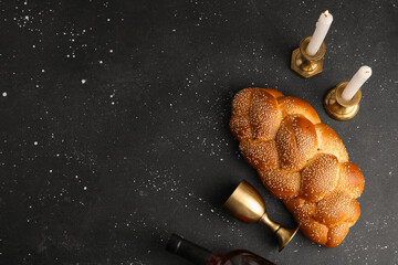 Fototapeta premium Traditional challah bread with wine and burning candles on dark background. Shabbat Shalom