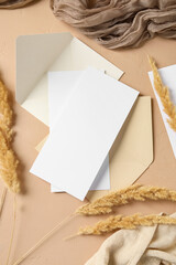 Fototapeta premium Envelopes with blank cards and pampas grass on beige background
