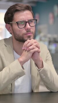 Pensive Young Man Sitting at Work Thinking, Vertical Video