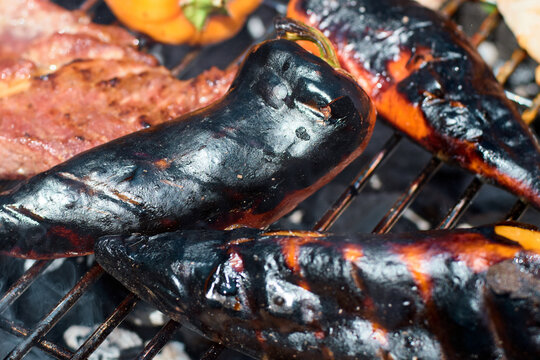 Close-up of charred bell peppers cooking on a hot metal barbecue grill grate