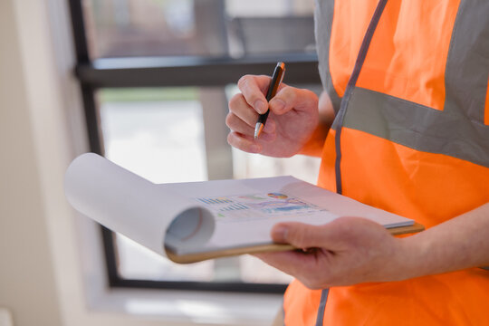 Warehouse worker reviewing and signing logistics documents representing inventory management, inspection, paperwork, supply chain operations, quality control industrial business workflow.