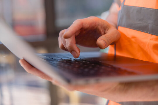 Industrial worker using a laptop for digital logistics and warehouse management, representing smart technology, inventory control, supply chain operations, data processing modern workflow.