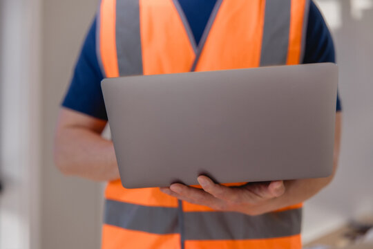 Industrial worker using a laptop for digital logistics and warehouse management, representing smart technology, inventory control, supply chain operations, data processing modern workflow.
