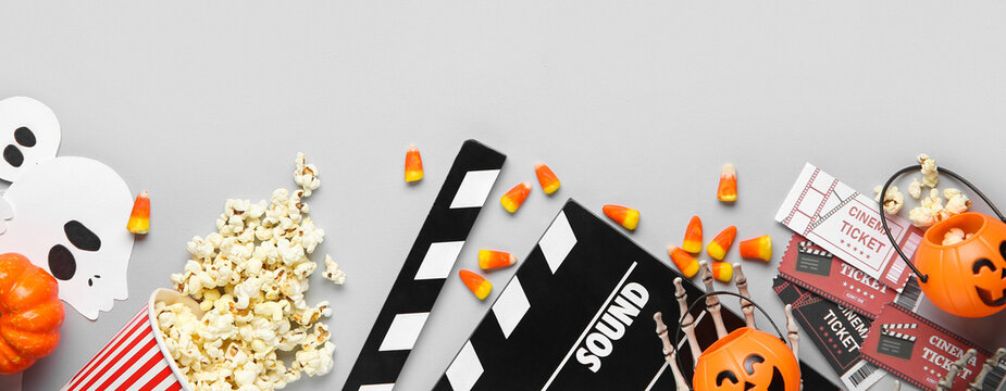 Halloween movie night flat lay with popcorn, candy corn, cinema tickets, and spooky decorations on a gray background