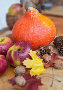  red apples  and orange pumpkin background with  walnuts and autumnal leaves on a wooden  table