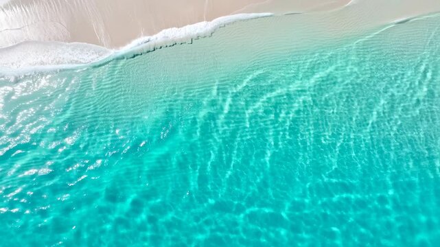 Overhead tropical shoreline with shallow turquoise water, pale sand, delicate wavelets, soft foam, shimmering sunlight, and clear coastal textures in calm tropical seascape