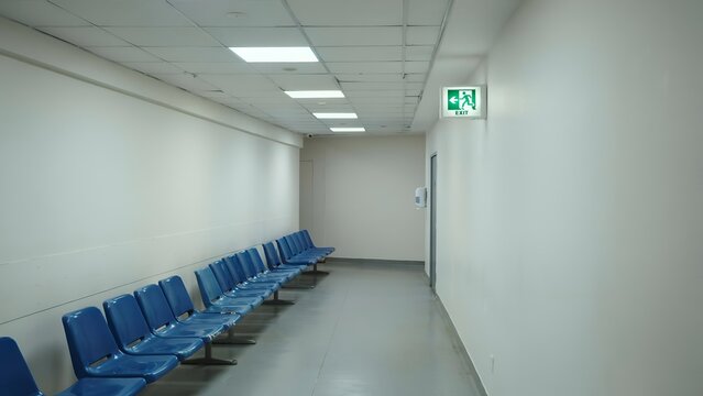 Empty waiting area with blue plastic chairs in a long hospital or office corridor