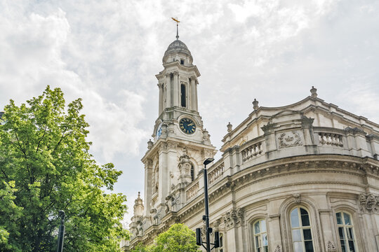 View of the historic St. Mary-le-Bow church tower with its ornate clock and stone facade set against a cloudy sky in London, England, United Kingdom.