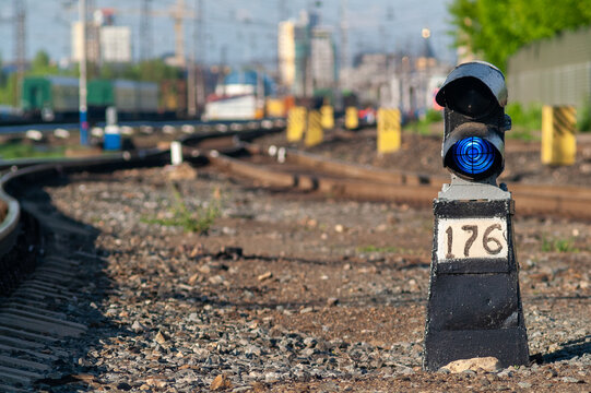 A blue railway signal lamp next to winding railway tracks and kilometre marker 176 at the town station.