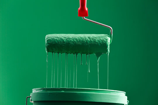 Green Paint Roller with Dripping Paint on Paint Bucket