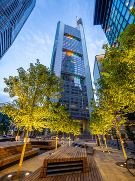 Illuminated trees stand before the Omnitower in Frankfurt at dusk